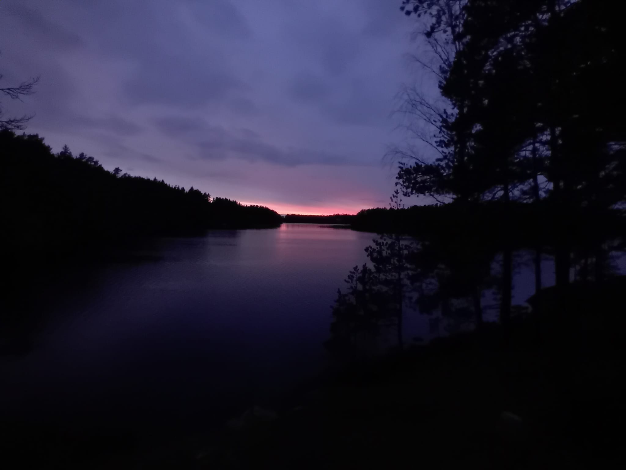 A purple evening sky reflected in a quiet forest lake